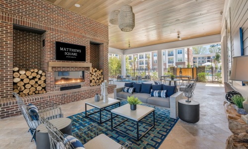 a clubroom with a tv, fireplace, a couch and chairs