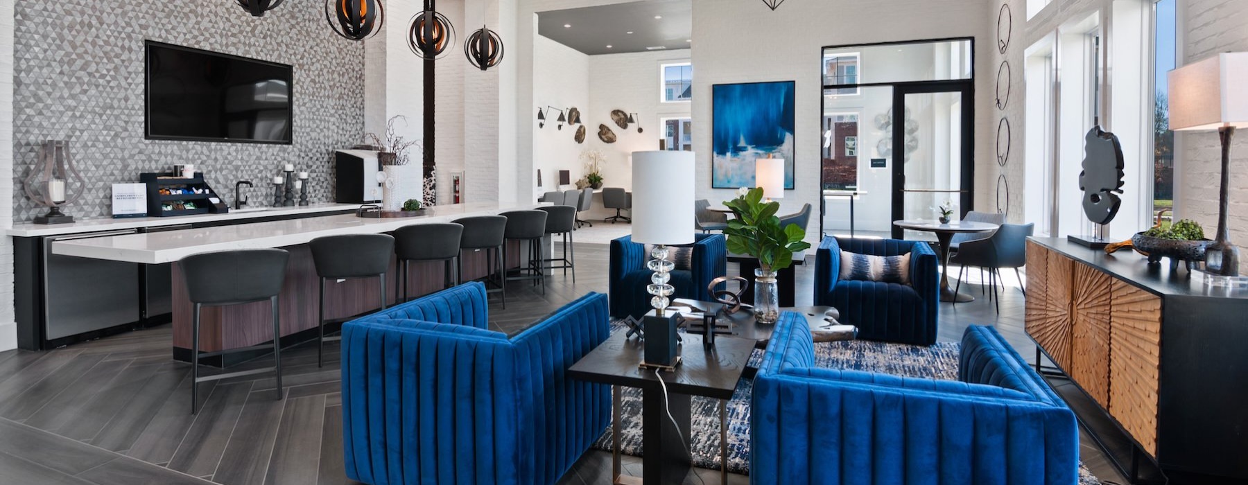 a clubroom with a kitchen area, a tv, tables and chairs